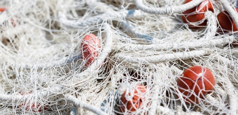Close-up of fishing net with red floats on the float line, fisheries concept background.